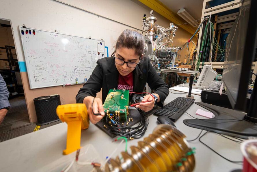 A scientist testing electronics that are part of the experimental setup used for making qubits in silicon in a lab.