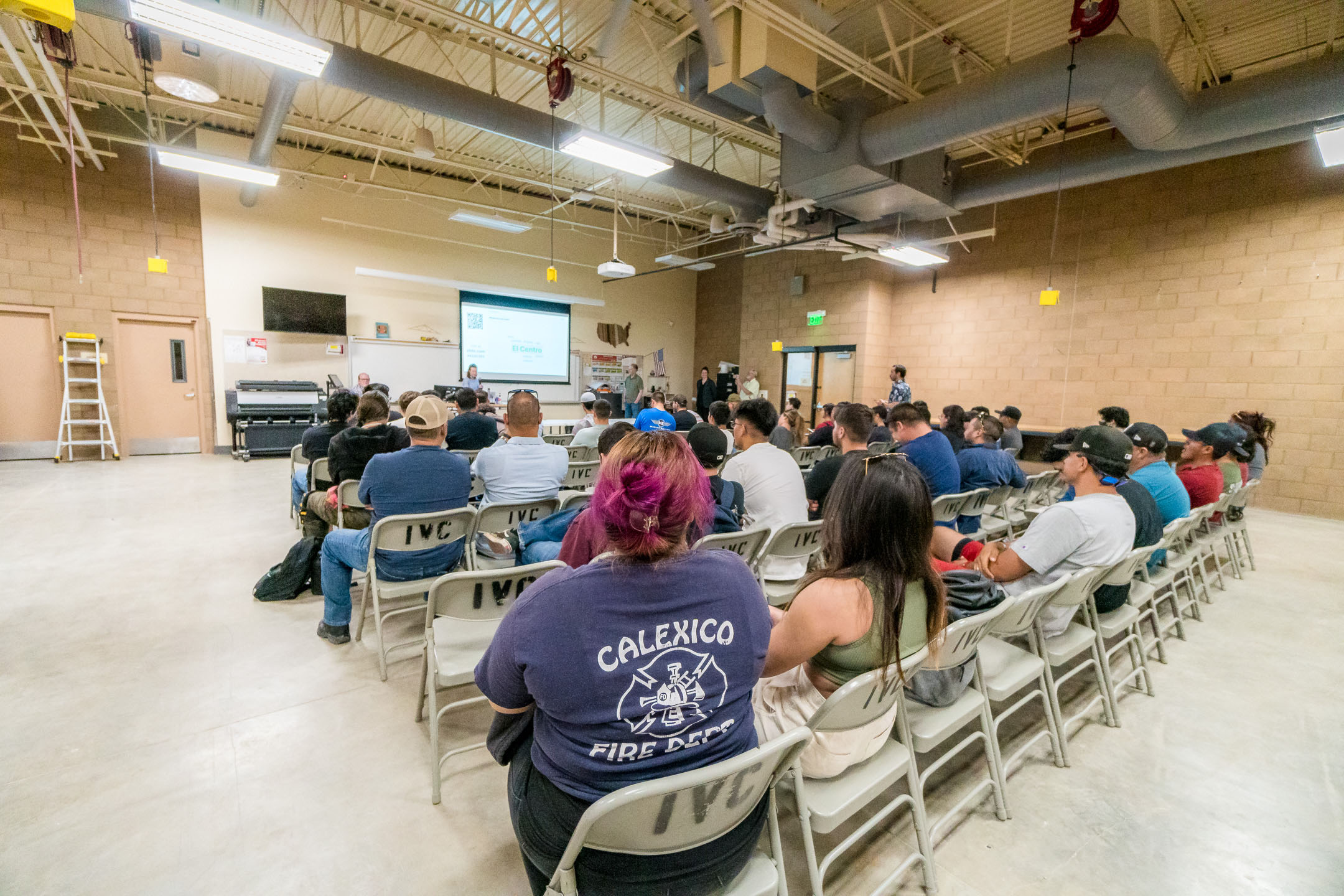 A group of people sitting in chairs in a room listening to a presentation.