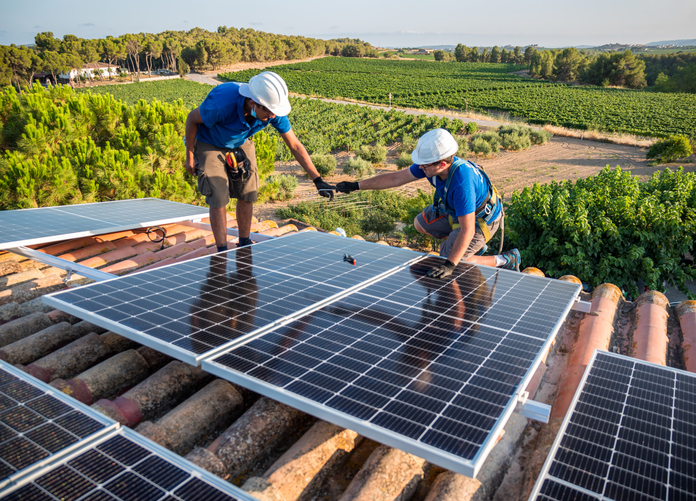 two technicians passing each other a tool while installing a solar panel