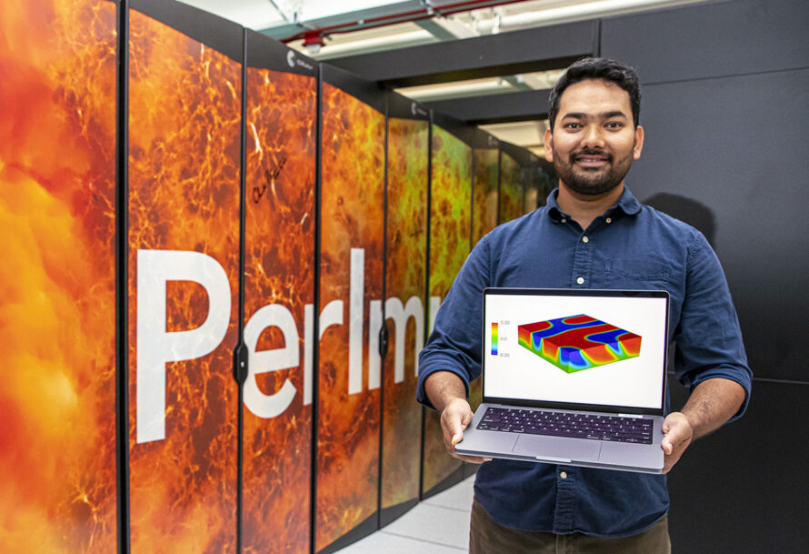 Prabhat Kumar holding a computer with a simulation in front of a super computer.