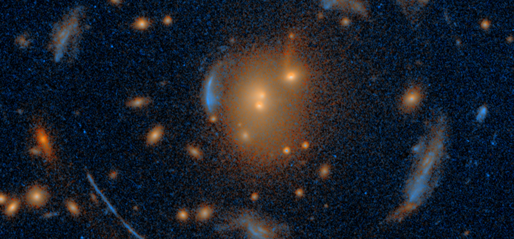 The Carousel Lens, an alignment consisting of 1 foreground galaxy cluster (the ‘lens’) and 7 background galaxies spanning immense cosmic distances through the gravitationally distorted space-time around the lens, as seen through the Hubble Space Telescope.