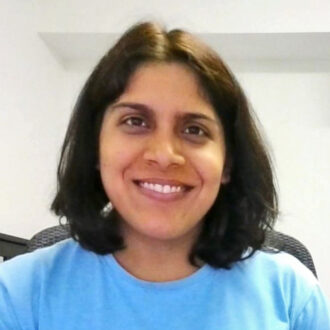 Portrait of a person with shoulder-length brown hair, wearing a blue shirt, smiling.