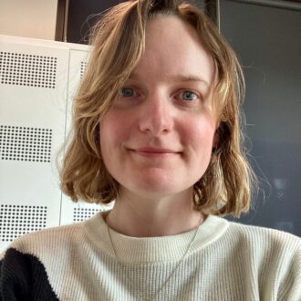 Portrait of Laura Cook, a person with short blonde hair wearing a cream top, smiling.