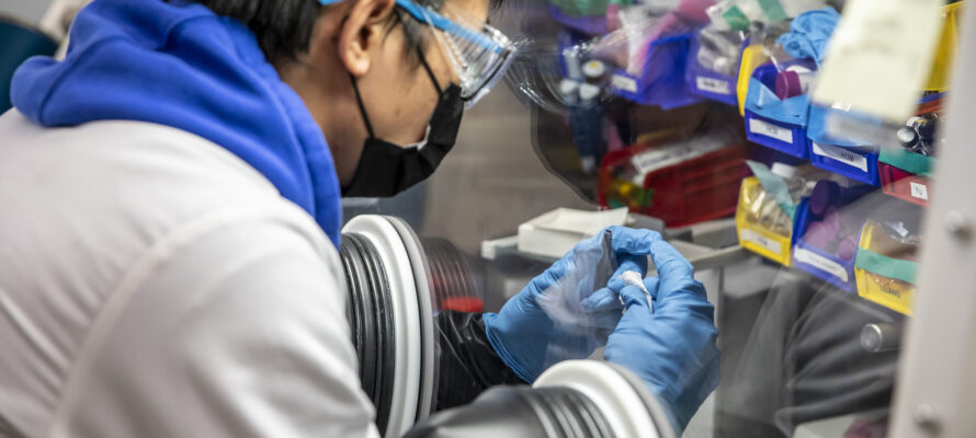 A scientist holds a sample in a fume hood.