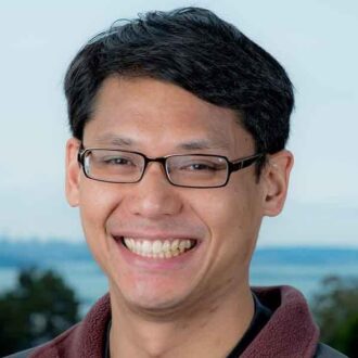 Emory Chan, a person with short black hair wearing The North Face jacket with black glasses, smiling.